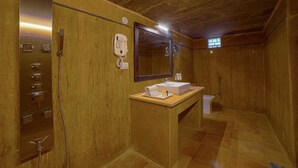 A bathroom with a wooden interior, a sink with toiletries, a mirror, and a shower area. - Heritage resort  (Jaisalmer)