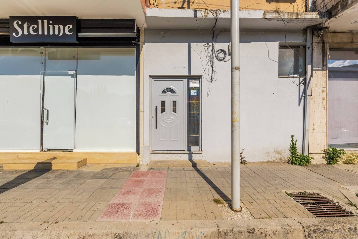 Une devanture de magasin avec une enseigne indiquant « Stelline », une porte blanche avec un panneau en verre et un poteau en métal.