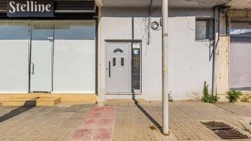 Une devanture de magasin avec une enseigne indiquant « Stelline », une porte blanche avec un panneau en verre et un poteau en métal.