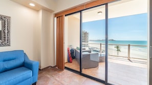 Ein Balkon mit Blick auf den Strand und ein Gebäude in der Ferne.