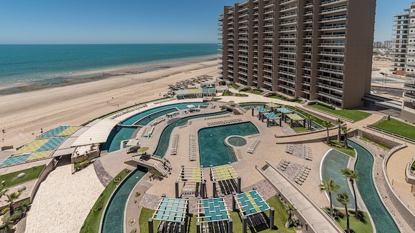 Ein Resort mit mehreren Schwimmbecken, einem Strandzugang und Hochhäusern.