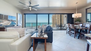 A modern hotel room with a balcony, a dining area, and a seating area with a view of the ocean. - Las Palomas Phase II Coronado 801 Exceptional oceanfront 2BR 2BA Unit (Puerto Peñasco)