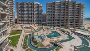 A high-rise hotel with multiple balconies, a central swimming pool, and a beach area. - Las Palomas Phase II Coronado 801 Exceptional oceanfront 2BR 2BA Unit (Puerto Peñasco)