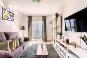 Ein modernes Wohnzimmer mit einer Couch, einem Couchtisch, einem Fernseher und Blick ins Freie.