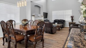 A spacious living room with a dining table, chairs, a sofa, and a fireplace. - 3BR Spacious Home with BBQ Patio,Backyard,Sleeps 6 (Aurora)