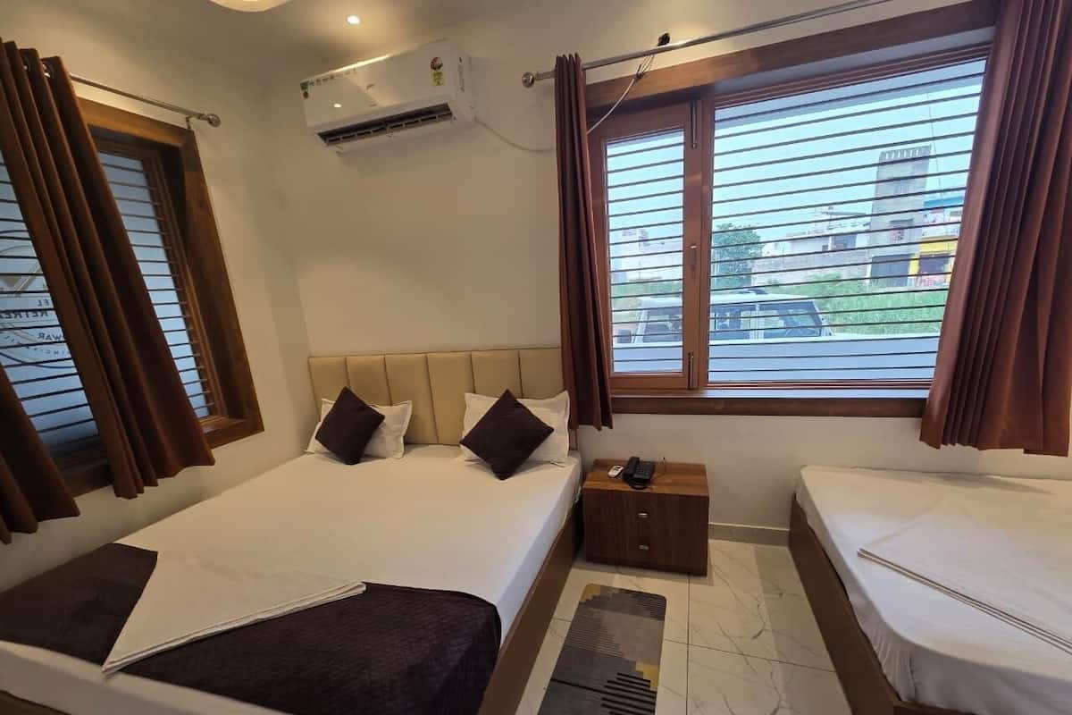 Habitación de hotel con dos camas, una mesita de noche con teléfono y un equipo de aire acondicionado.