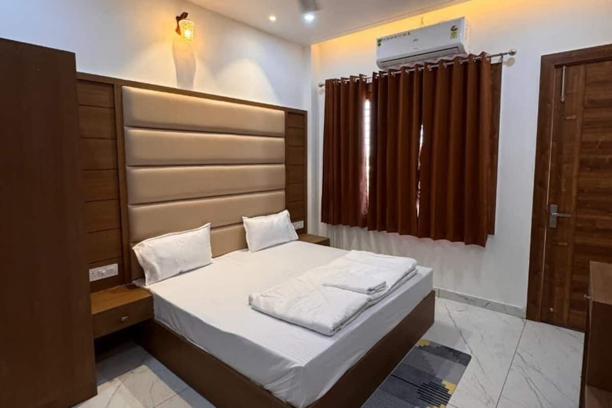 Un dormitorio con cama, ventilador de techo, aire acondicionado y ventana con cortinas.