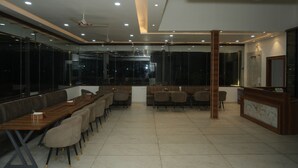 A conference room with a long table, chairs, a reception desk, and a ceiling fan. - Hotel Baromas Retreat (Haridwar)