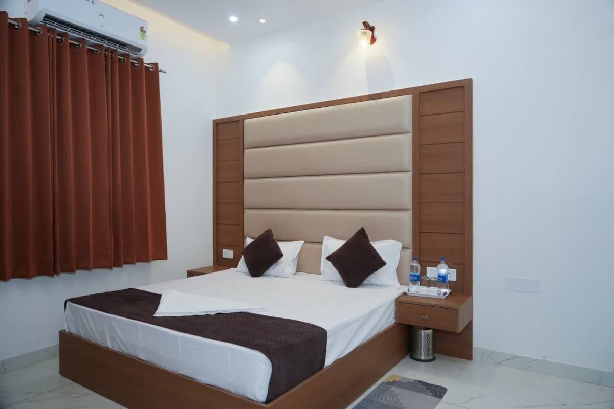 Habitación de hotel con una cama grande, una mesita de noche, aire acondicionado de pared y una ventana con cortinas.