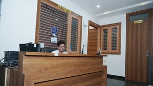 A reception desk with a wooden finish, a sign indicating no smoking, and a sign for the washroom. - Hotel Baromas Retreat (Haridwar)