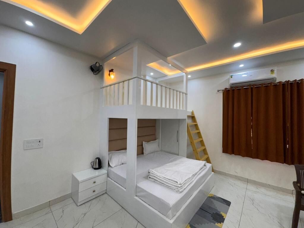 Quarto com beliche, mesa de cabeceira, escada e janela com cortinas.