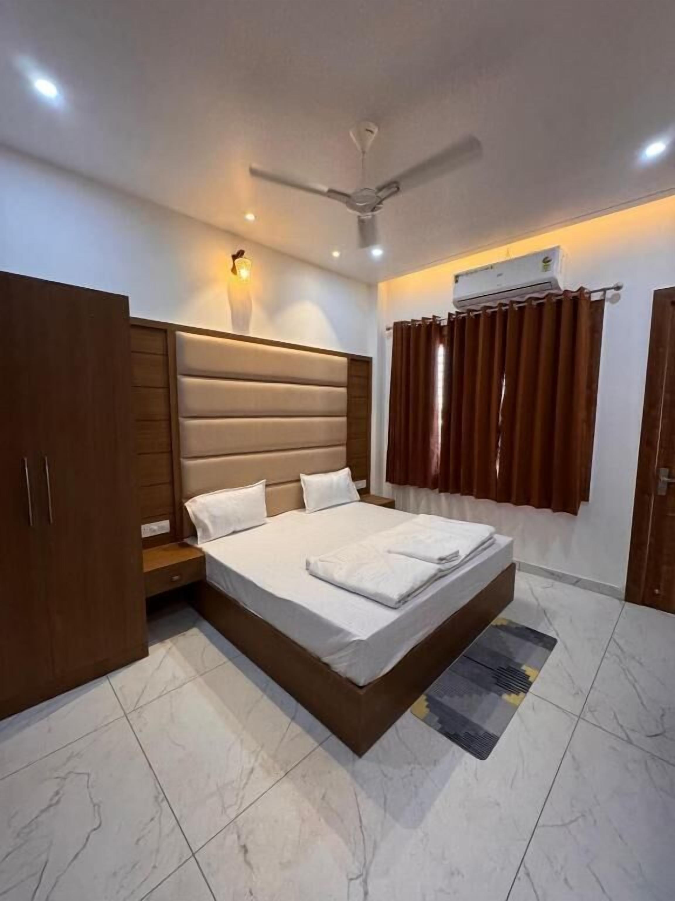 Un dormitorio con cama, armario, ventilador de techo, aire acondicionado y cortinas.