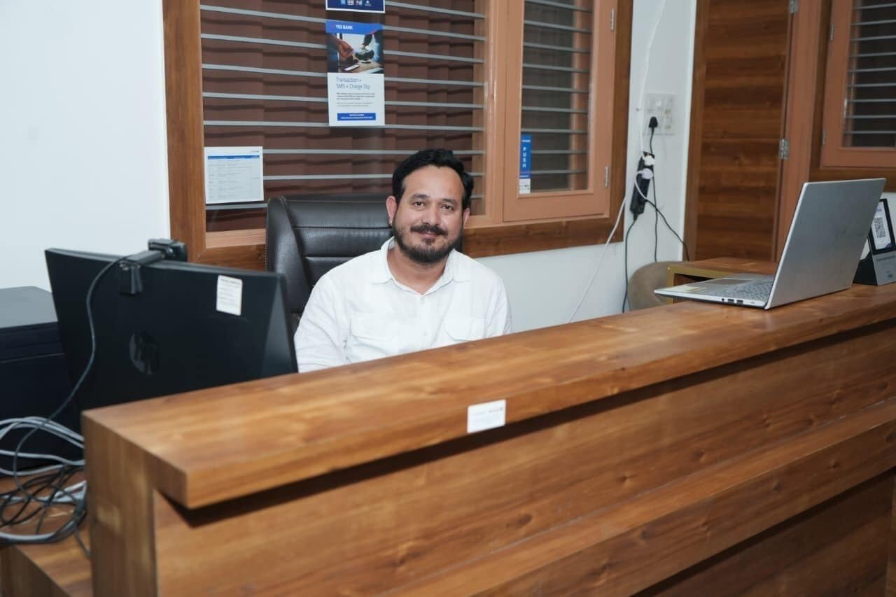 A reception desk with a computer, a laptop, and a wooden counter.