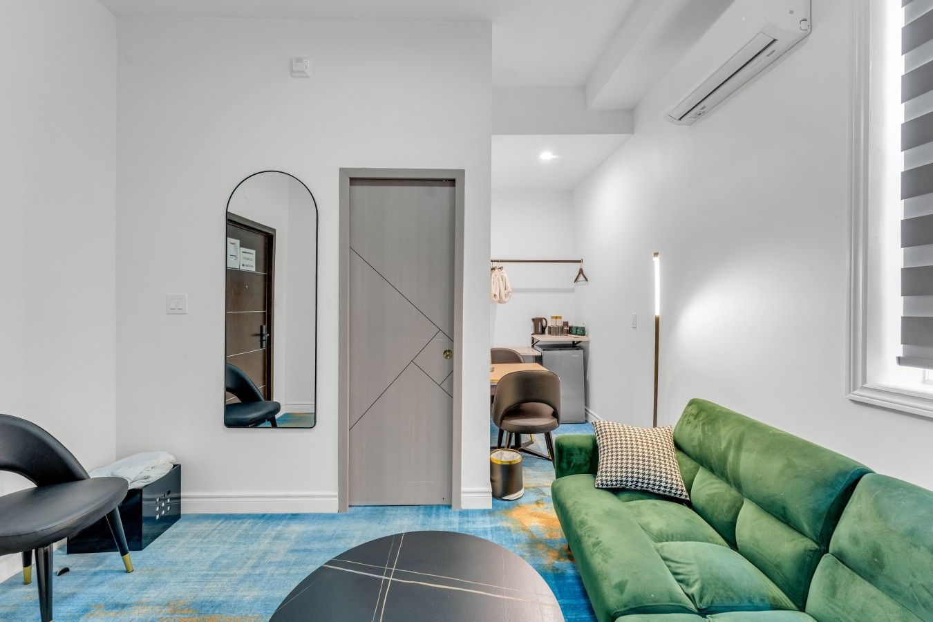 A modern living room with a green sofa, a black exercise ball, and a dining area with a table and chairs.