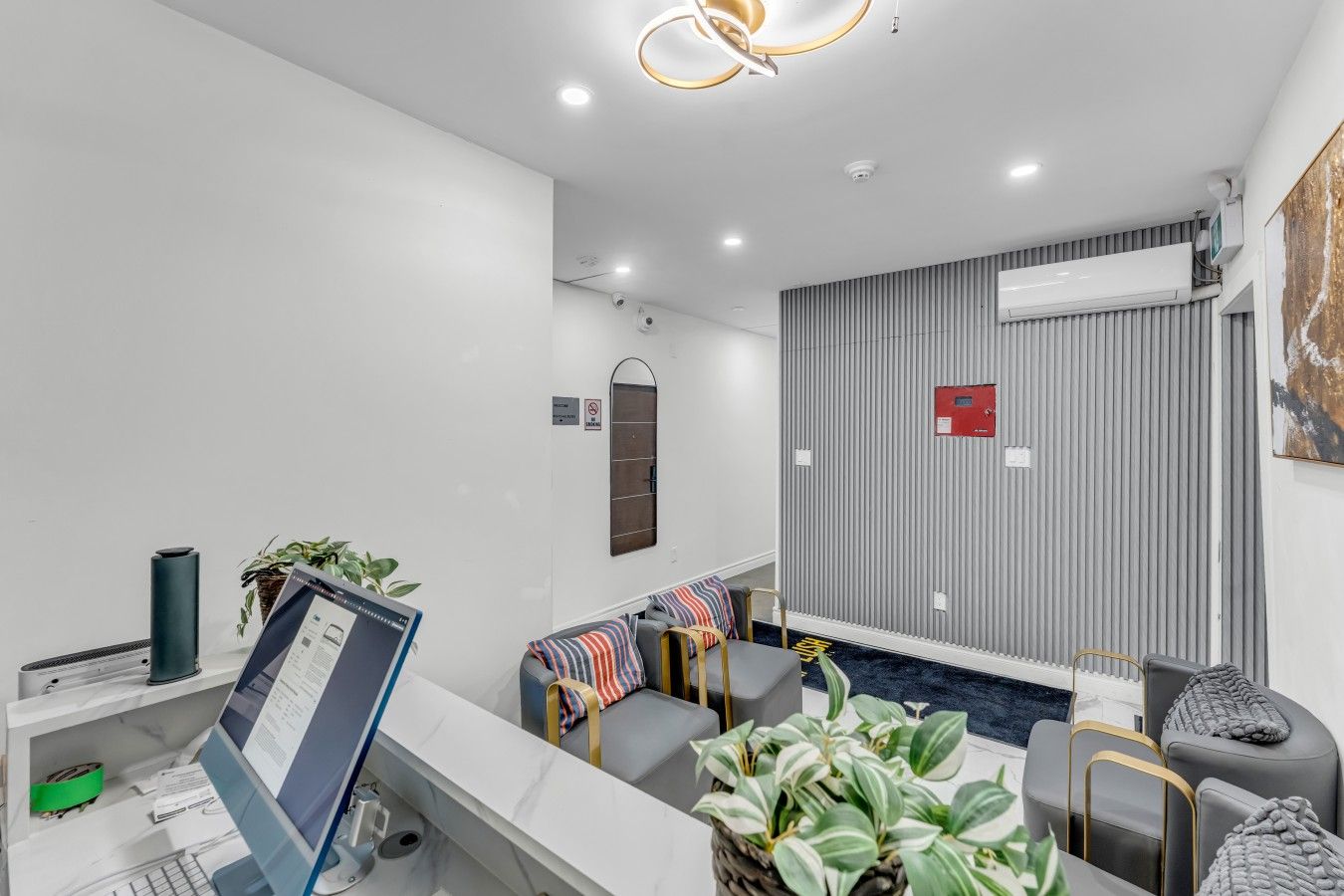 A modern hotel lobby with a reception desk, seating area, and a wall-mounted air conditioning unit.