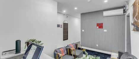 A modern hotel lobby with a reception desk, seating area, and a wall-mounted air conditioning unit.