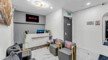 A modern reception area with a Netflix sign, a reception desk, seating, and a door with a 'No Smoking' sign.
