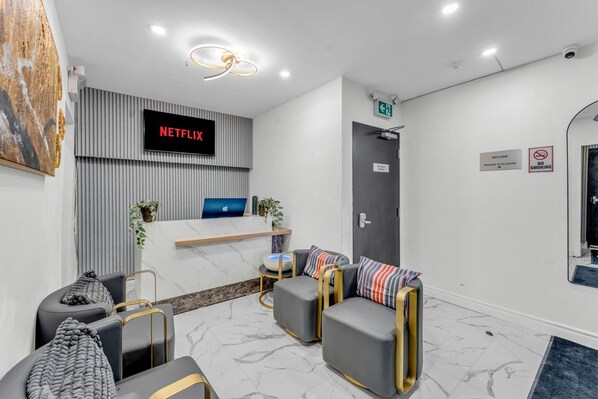 A modern reception area with a Netflix sign, a reception desk, seating, and a door with a 'No Smoking' sign.