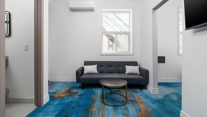 A modern living room with a sofa, a round coffee table, and a large window. - Executive Double Room ; Boutique Hotel• Trinity Bellwoods. Downtown Toronto (Toronto)