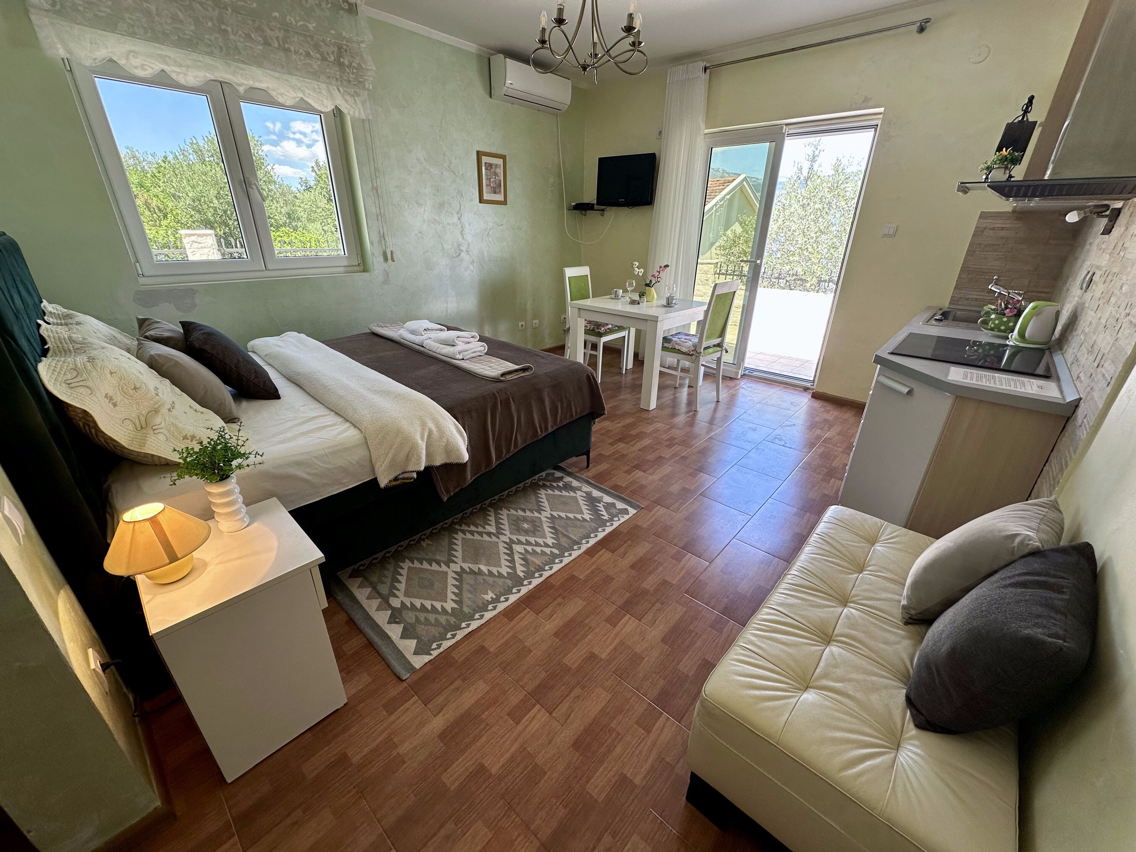 A bedroom with a bed, bedside table, and a small desk with a lamp.