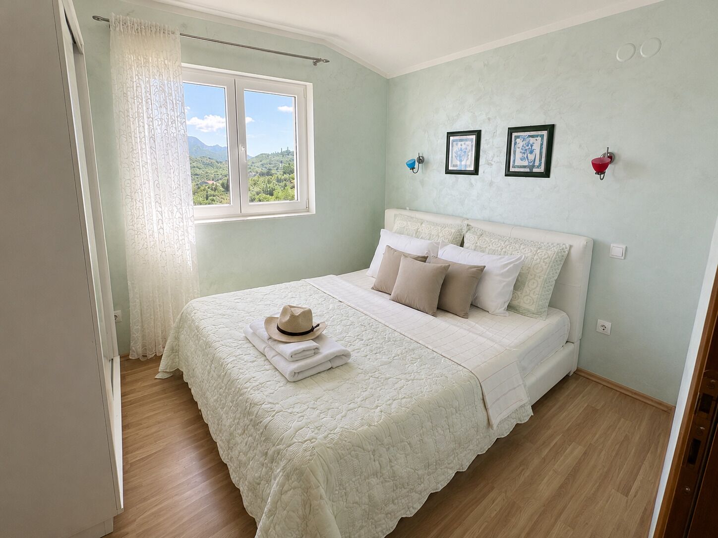 Un dormitorio con una cama, una ventana con cortinas e imágenes enmarcadas en la pared.
