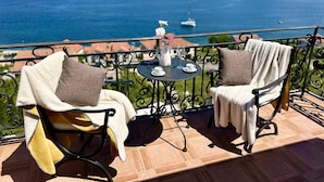 A balcony with two chairs, a small table, and a view of the sea and mountains. - Villa Mare (Krasici)