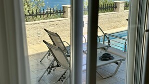 A balcony with a pool, a chair, and a hat on the table. - Villa Mare (Krasici)