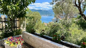 A garden with flower beds and a view of the sea. - Villa Mare (Krasici)