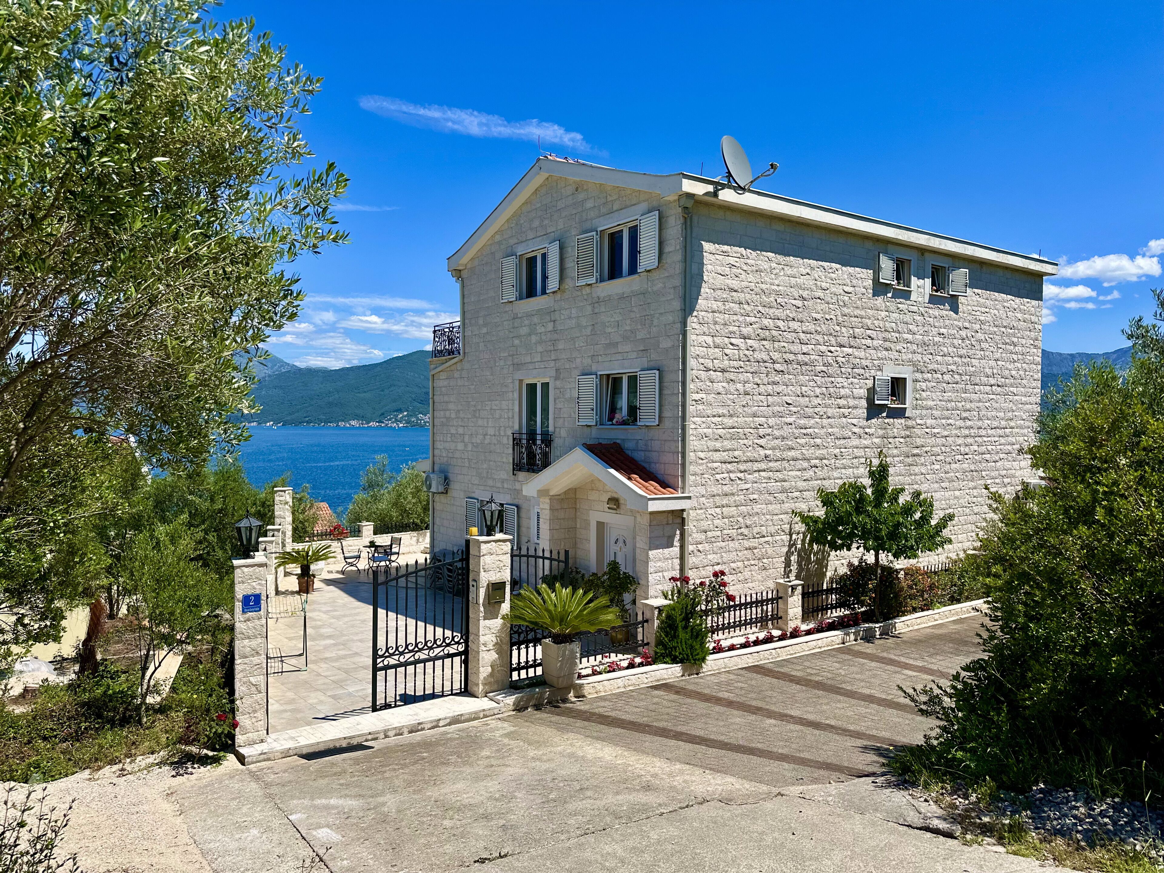 A stone building with a balcony, a gate, and a view of the sea.