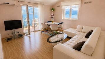 Un salon comprenant un canapé, un téléviseur, une table à manger, des chaises et un balcon avec vue.
