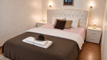 A neatly made bed with a brown and white bedspread, a white headboard, and two bedside tables with lamps.
