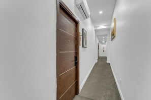 A hallway with a wooden door, white walls, and a carpeted floor.