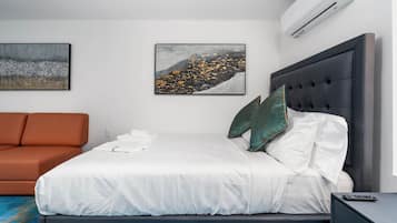 A modern hotel room with a bed, a sofa, and two paintings on the wall.