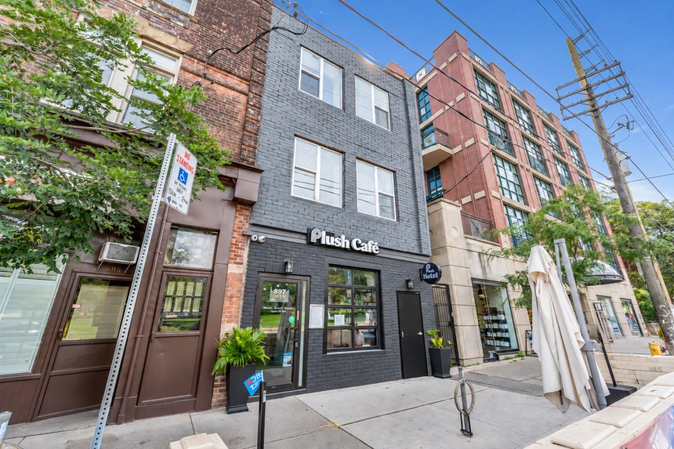 A building with a 'Plush Café' sign, a visible storefront, and a 'No Standing' sign.