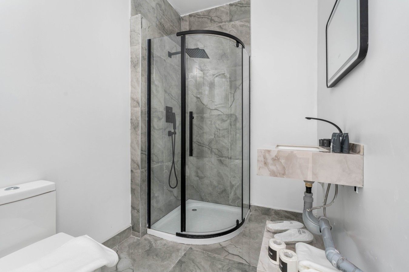 Une salle de bain moderne avec une douche à parois de verre, des toilettes et un lavabo doté d'un plan de travail en marbre.