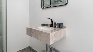 A bathroom with a marble sink, a mirror, and toiletries.