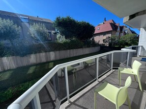 A balcony with a glass railing, a small table, and two chairs. - Central Apartment Near the Beach (Koksijde)