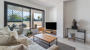 Ein modernes Wohnzimmer mit Sofa, Couchtisch, Fernseher und einem kleinen Tisch mit einer Statue.