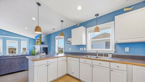 A modern kitchen with white cabinets, a wooden countertop, and pendant lighting. - Soundside, Dog Friendly Home in Avon with Hot Tub (Avon)