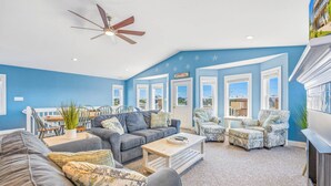 A living room with a ceiling fan, a sofa, a coffee table, and patterned chairs. - Soundside, Dog Friendly Home in Avon with Hot Tub (Avon)