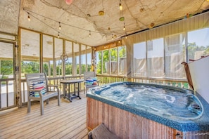 Eine Holzterrasse mit Whirlpool, Stühlen und Barbereich mit Blick auf Grünflächen.