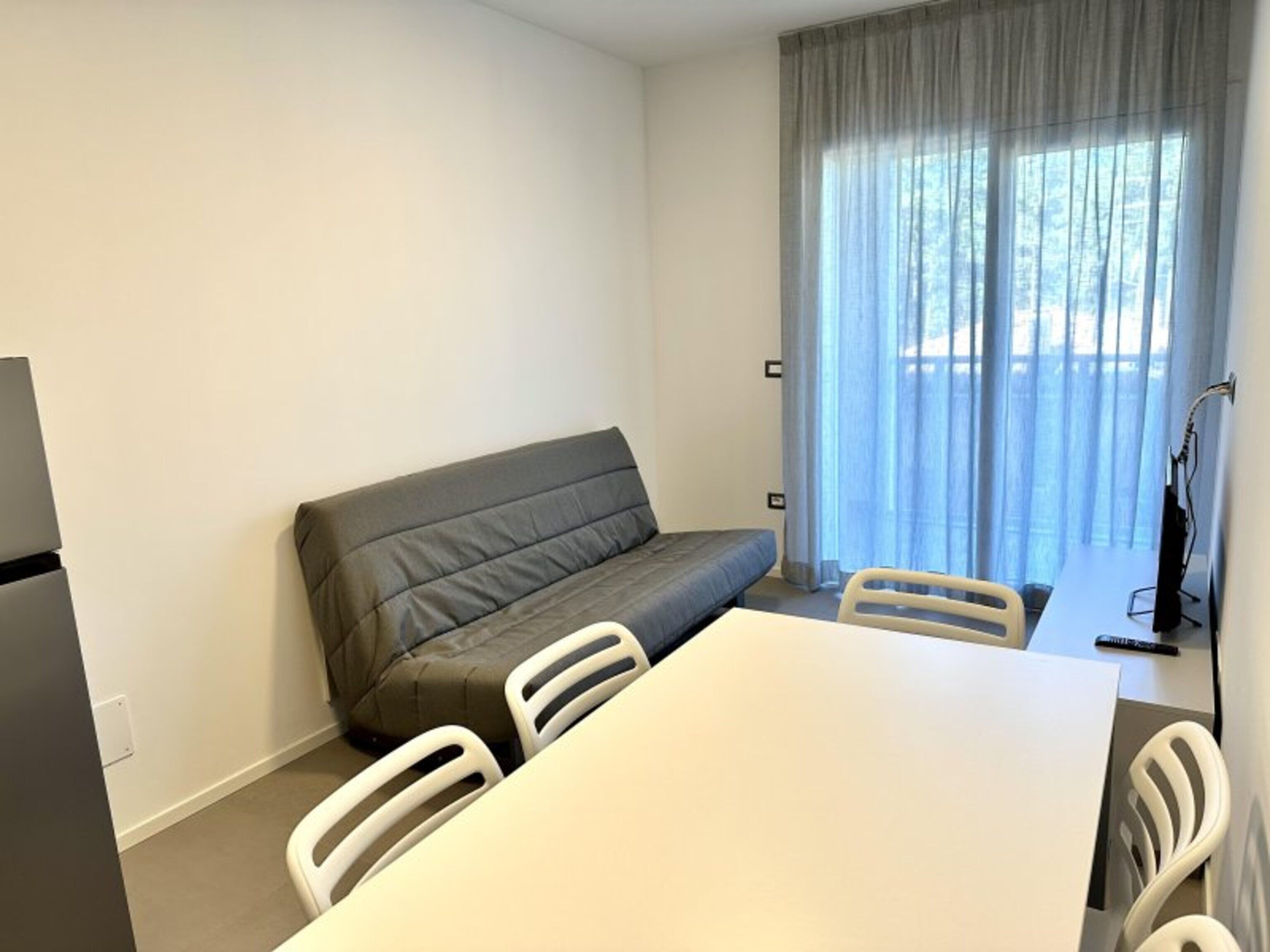 Um quarto pequeno com sofá, mesa e cadeiras.