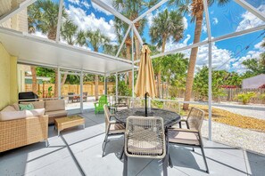 Eine überdachte Terrasse mit Gartenmöbeln, einem Tisch und Stühlen.