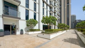 A modern building with a courtyard, large windows, and a few trees. - Breathtaking Skyscraper Views 3BR, Just a Stone Throw from Burj Khalifa, Dubai Mall (Dubai)