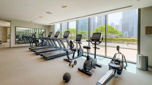 A gym with treadmills, elliptical machines, and a rowing machine, large windows with a city view, and a mirrored wall. - Breathtaking Skyscraper Views 3BR, Just a Stone Throw from Burj Khalifa, Dubai Mall (Dubai)