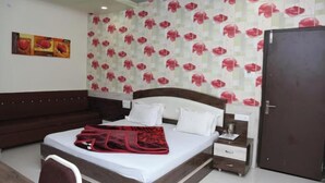 Une chambre d’hôtel avec un lit, une table de chevet, une commode, un canapé marron et une porte.