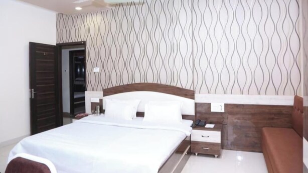 Une chambre à coucher avec un lit, des tables de chevet, une commode, un ventilateur de plafond et un mur décoré d’un motif.