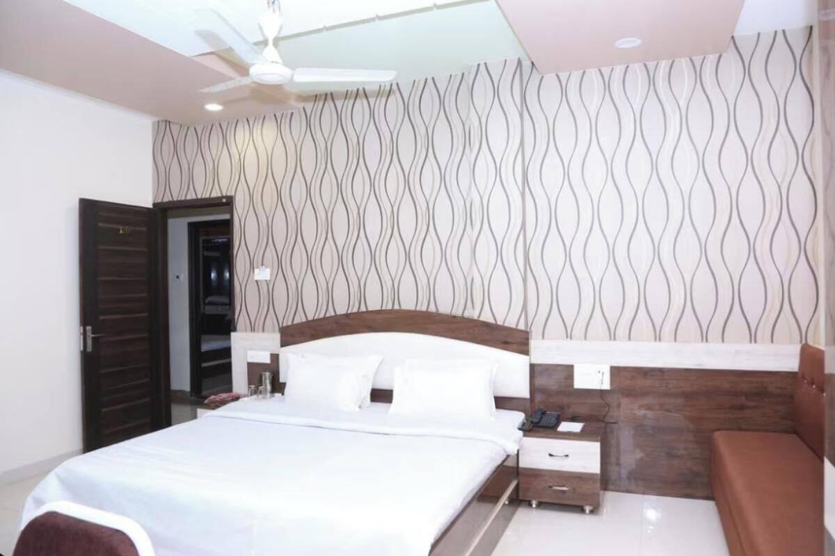 Un dormitorio con cama, mesitas de noche, un ventilador de techo y una pared decorada.
