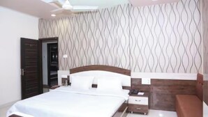 Une chambre à coucher comprenant un lit, des tables de chevet, une commode, un ventilateur de plafond et un mur décoré d’un motif.