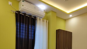 A hotel room with a bed, a wardrobe, an air conditioner, and a window with curtains. - The Nirvana Resort (Chatra)